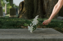 Χέρι που επαναποθέτει λουλούδια σε τάφο