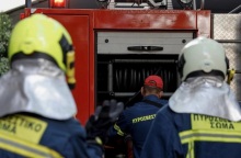 Πυροσβέστες φορούν τη στολή τους και στέκονται πίσω από όχημα, έτοιμοι να επιχειρήσουν για την κατάσβεση φωτιάς