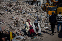 Κάτοικοι στην πόλη Χατάι της Τουρκίας κάθονται δίπλα από έναν σωρό με ερείπια μετά τον σεισμό