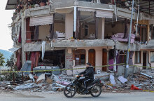 Νεαρός στην πόλη Χατάι περνά με το μηχανάκι μπροστά από κτίριο που έχει υποστεί ζημιές από τον σεισμό στην Τουρκία