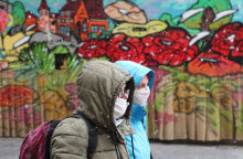 Άνθρωποι με μάσκα για τον κορωνοϊό μπροστά από mural για την πανδημία covid στο Σεράγεβο