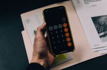 Γυναίκα κρατά στα χέρια της το τηλέφωνό της έτοιμη να υπολογίσει 