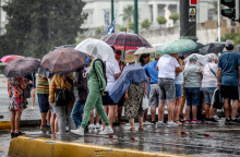 Τουρίστες κρατάνε ομπρέλες στο κέντρο της Αθήνας