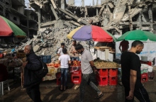 Διάφοροι Παλαιστίνιοι περνούν μπροστά από πάγκους με τρόφιμα που έχουν στηθεί δίπλα σε κατεστραμμένα κτίρια την τελευταία Παρασκευή του Ραμαζανιού κατά μήκος ενός δρόμου στον προσφυγικό καταυλισμό Al Nusairat, στη Λωρίδα της Γάζας