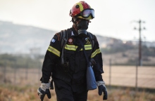 Πυροσβέστης με μπλε στολή, κράνος, μάσκα και γυαλιά προστασίας σε πυρκαγιά στην Λαμία