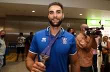 Ο Στέφανος Ντούσκος κρατώντας ένα μεταλλείο φορώντας μπλε αθλητική μπλούζα