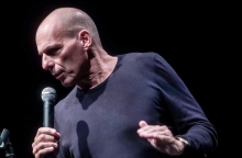 Ο Γιάννης Βαρουφάκης μιλάει όρθιος με μικρόφωνο