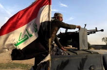 Ιρακινός κάθεται πάνω σε τεθωρακισμένο όχημα με την ιρακινή σημαία