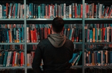 Άνδρας όρθιος μπροστά από βιβλιοθήκη γεμάτη βιβλία