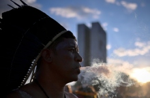 άνδρας με φτερά στο κεφάλι φυσάει καπνό - στο βάθος διπλή πολυκατοικία