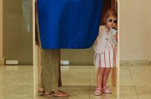 Ένα κοριτσάκι φαίνεται στην άκρη του παραβάν την ώρα που η μητέρα της ψηφίζει