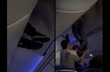 εσωτερικο αεροπλανου, επιβατες βοηθουν ανδρα να ξεκολλησει απο ντουλάπι χειραποσκευών