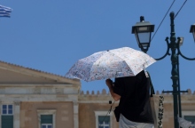 αθηναιος με ομπρελα μπροστα στη Βουλη, ελληνικη σημαια