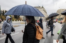 κοσμος περπαταει κρατώντας ομπρελες