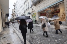 Πολίτες με ομπρέλες περπατούν υπό βροχή στην Ερμού