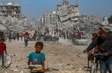 Παλαιστίνιοι περπατούν ανάμεσα σε ερείπια κτιρίων εν μέσω εκεχειρίας μεταξύ Ισραήλ και Χαμάς, στην πόλη της Γάζας
