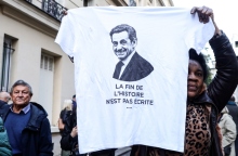 Μια γυναίκα κρατάει ένα μπλουζάκι με το πορτρέτο του πρώην Γάλλου προέδρου Νικολά Σαρκοζί και το μήνυμα «Το τέλος της ιστορίας δεν έχει γραφτεί ακόμα» κατά τη διάρκεια διαδήλωσης κοντά στην κατοικία του πρώην Γάλλου προέδρου την ημέρα που πρόκειται να εισέλθει στη φυλακή