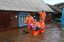 Mέλη του ρωσικού Υπουργείου Έκτακτης Ανάγκης μεταφέρουν ένα παιδί από πλημμυρισμένο σπίτι 
