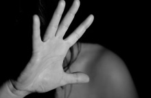 Γυναίκα προστατεύει με τα χέρια της το πρόσωπό της από τον κακοποιητή της