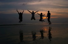 Άνθρωποι στην παραλία που χοροπηδούν