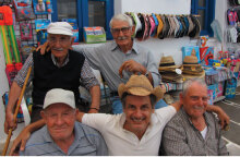 Ο Dimitris Dassios καθισμένος στο παγκάκι ανάμεσα σε φίλους στο νησί