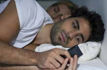 guy-checking-cell-in-bed.jpg