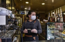 Γυναίκα με προστατευτική μάσκα και γάντια σε καφέ