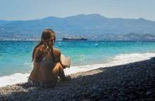 Κοπέλα διαβάζει βιβλίο μπροστά στη θάλασσα