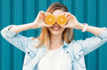 Κορίτσι που κρατάει ροδέλες πορτοκαλιού μπροστά στα μάτια της