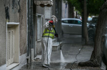 Υπάλληλος του Δήμου Αθηναίων με προστατευτική στολή για τον κορωνοϊό απολυμαίνει πεζοδρόμιο στο κέντρο της Αθήνας