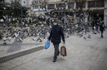 Ηλικιωμένος άνδρας με προστατευτική μάσκα για τον κορωνοϊό περπατά στο κέντρο της Αθήνας, κουβαλώντας τσάντες με ψώνια