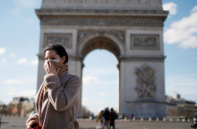 Γυναίκα με μάσκα για τον κορωνοϊό στο Παρίσι με φόντο την Αψίδα του Θριάμβου