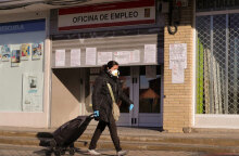 Κορωνοϊός στην Ισπανία: Γυναίκα με προστατευτική μάσκα περνά μπροστά από γραφείο ευρέσεως εργασίας στη Μαδρίτη