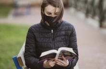 Γυναίκα διαβάζει βιβλίο φορώντας μάσκα