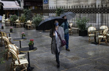Κορωνοϊός στη Γαλλία: Πολίτες με ομπρέλες περπατούν σε πλακόστρωτο δρόμο στο Παρίσι