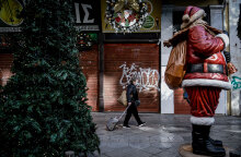 Κορωνοϊός και Χριστούγεννα: Γυναίκα με προστατευτική μάσκα σέρνει βαλίτσα σε πεζόδρομο