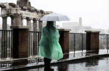 Τουρίστρια με ομπρέλα και αδιάβροχο έξω από τη Ρωμαϊκή Αγορά