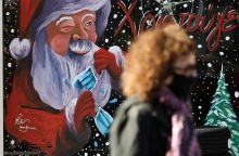 Γυναίκα με μάσκα μπροστά από χριστουγεννιάτικη βιτρίνα