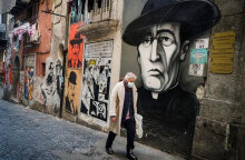 Ιταλία - Covid-19: Άνδρας με προστατευτική μάσκα για τον κορωνοϊό περνά μπροστά από γκράφιτι