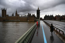 Γυναίκα με μάσκα για τον κορωνοϊό διασχίζει τη γέφυρα Westminster στο Λονδίνο εν μέσω lockdown για τον κορωνοϊό