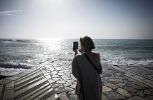 Γυναίκα με μάσκα κάνει βόλτα στη θάλασσα και φωτογραφίζει