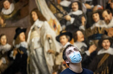 Άμστερνταμ - Rijksmuseum: Νεαρός με μάσκα για τον κορωνοϊό με φόντο τον πίνακα «Νυχτερινή περίπολος» του Ολλανδού ζωγράφου Ρέμπραντ
