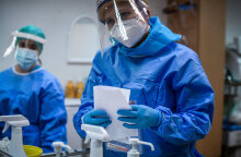 Εμβολιασμοί για τον κορωνοϊό στην Ελλάδα: Υγειονομικοί με μάσκα, ασπίδα, και προστατευτική στολή