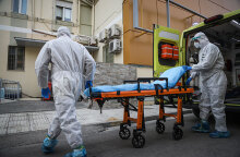 Υγειονομικοί του ΕΚΑΒ με προστατευτικές στολές ετοιμάζονται να μεταφέρουν σε φορείο νέο ασθενή με κορωνοϊό