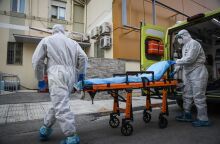 Υγειονομικοί του ΕΚΑΒ με προστατευτικές στολές ετοιμάζονται να μεταφέρουν σε φορείο νέο ασθενή με κορωνοϊό