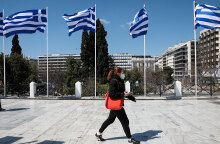 Γυναίκα με μάσκα για τον κορωνοϊό περνά από το Σύνταγμα όπου έχουν τοποθετηθεί ελληνικές σημαίες για τα 200 χρόνια από την Επανάσταση του 1821