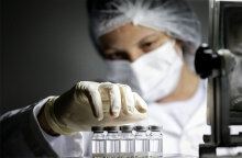 Υγειονομικός με μάσκα μεταφέρει εμβόλια για τον κορωνοϊό: Λιγότερες δόσεις από το εμβόλιο της δίνει στην ΕΕ η AstraZeneca σε σχέση με τα όσα είχαν συμφωνηθεί για τον Μάρτιο