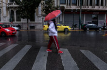 Αττική - Lockdown: Κοπέλα με ομπρέλα διασχίζει διάβαση πεζών στην Αθήνα