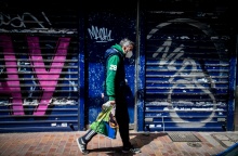 Πολίτης με μάσκα περπατά μπροστά από κλειστό κατάστημα