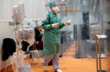 Υγειονομικός σε νοσοκομείο με προστατευτική στολή για τον κορωνοϊό διενεργεί τεστ για Covid-19 σε ηλικιωμένο άτομο